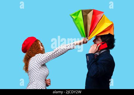 Black Friday Sale. Holiday Offer Discount. Addicted Shopaholic Girl with Colorful Paper Shopper Bags Hitting Bearded Man on Head Talking on Smartphone Stock Photo