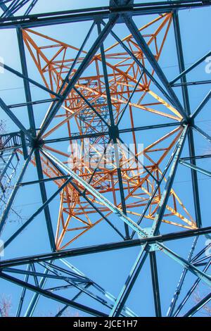 Close-up view of an electric tower with a beautiful blue sky background. Industrial engineering concept. Iron structure for high-voltage electrical en Stock Photo