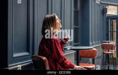 A young woman with a glass of wine on the terrace of a restaurant. Stock Photo