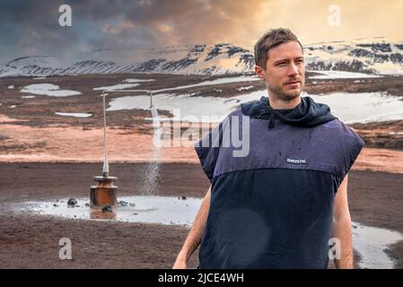 Thoughtful tourist looking away while standing against hot shower at Krafla Stock Photo