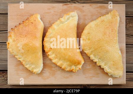 Three calzone pizzas on wooden board top view horizontal Stock Photo