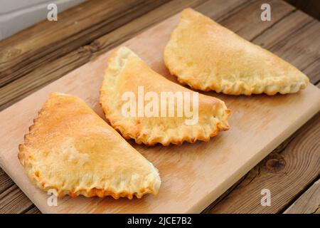 Three calzone pizzas on wooden plank horizontal Stock Photo