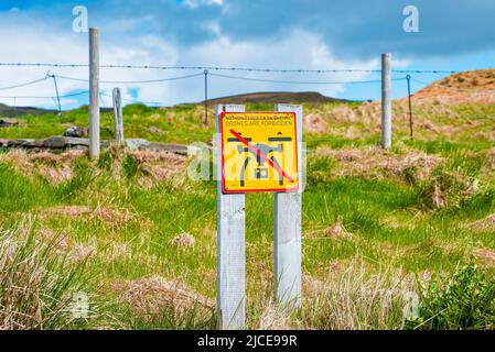 No drone flying sign on grassy landscape in protected valley against blue sky Stock Photo