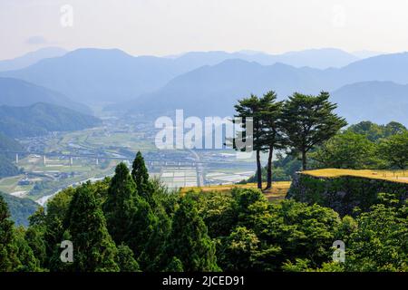 Trees atop ancient stone walls overlooking rural town in mountains Stock Photo