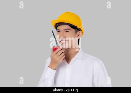 Portrait young asian man is engineer wearing helmet standing and using radio for speak with confident isolated on white background, handsome male is a Stock Photo