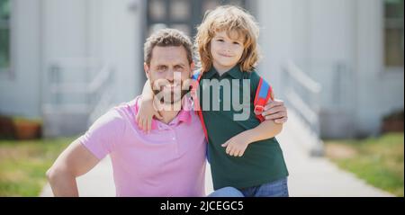 Father and son run with father after come back from school. Family, education and outdoor concept. Stock Photo