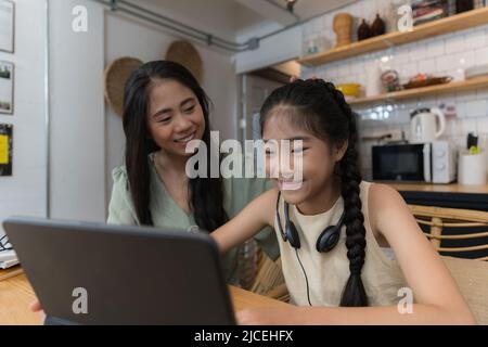 Family and home school concept. Asian mother teach her daughter using application on digital tablet at home. Stock Photo