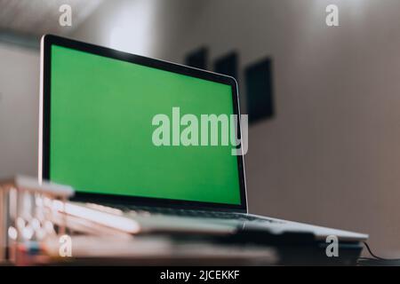 Laptop with green screen on a desk in the office Stock Photo
