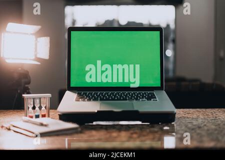 Laptop with green screen for adding images. In the background a notebook with a background of lights Stock Photo