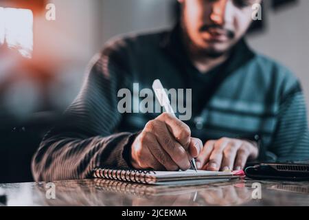 An inspired man jotting down ideas on a notebook Stock Photo