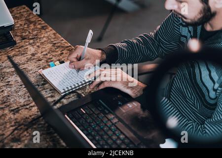 Young man taking notes from his virtual class Stock Photo