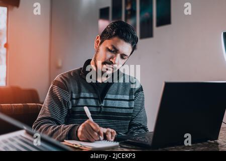 A man studying sitting behind his desk in the living room Stock Photo