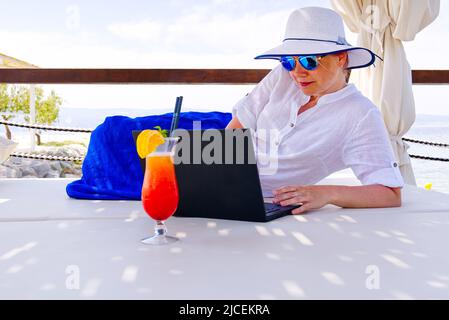 businesswoman handle buisness on her trip by laptop at summer vacation. Stock Photo