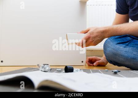 Professional Furniture Assembly Worker Assembles Shelf. Furniture assembly process. DIY Assembling Stock Photo