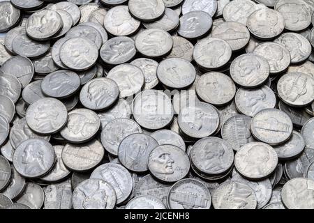A close up shot of a pile of various used modern clad (non-silver) USA Jefferson five cent nickels. Stock Photo