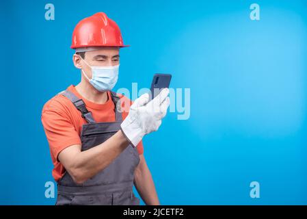 Male builder in face mask using smartphone during work Stock Photo