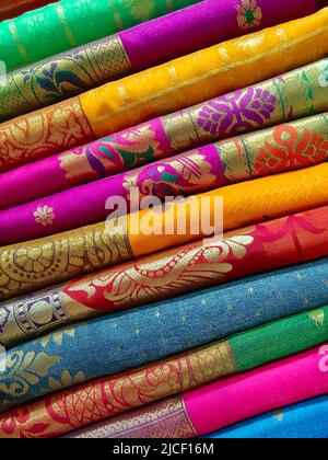 Closeup view of stacked colours saris or sarees in display of Indian retail shop, textile shop. Stock Photo