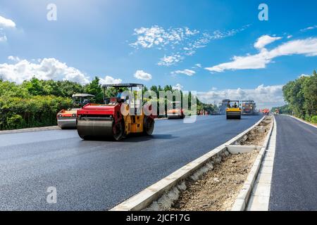 Construction site is laying new asphalt pavement, road construction workers and road construction machinery scene. Highway construction site scene. Stock Photo