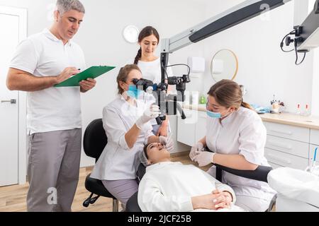 Group of students in dental clinic learn watching dental treatment with a microscope Stock Photo