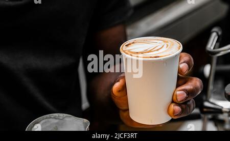 African Coffee Barista pouring a heart shape design with milk foam Stock Photo