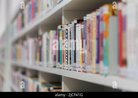 Stuttgart, Germany - Nov 16, 2021: Close-up of books in a bookshelf. Symbol for reading, literature, knowledge and information. Side view, Stock Photo