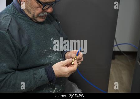 Mature technician installing water filter to an american fridge in kitchen. Stock Photo