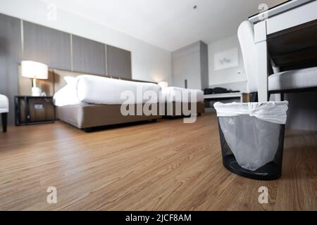 A container trash in the room with plastic inside it in hotel and resort bedroom with wooden floor and furniture background. Stock Photo