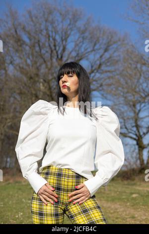 Woman with daisy in corner of mouth and looking sideways Stock Photo