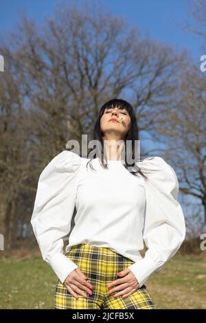 Woman with daisy in corner of mouth and eyes closed Stock Photo