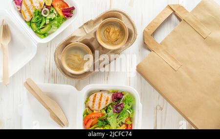 Takeaway food. Fresh salad and coffee on white wooden background. Top view. Stock Photo