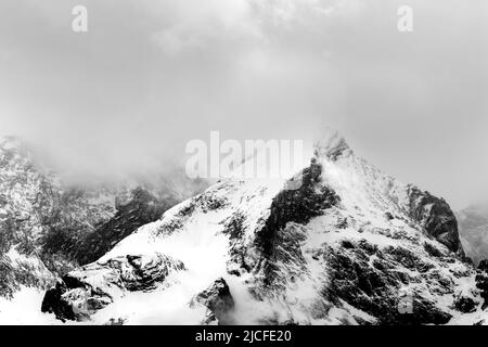 Bad weather with snow and dense clouds with fog at the Alpspitze above Garmisch-Partenkirchen. Seen from Krün. Stock Photo