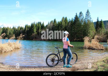 young woman riding mountain bike at Geroldsee in Buckelwiesen near Krün, Germany, Bavaria, Upper Bavaria, Isartal, road, path, bicycle Stock Photo