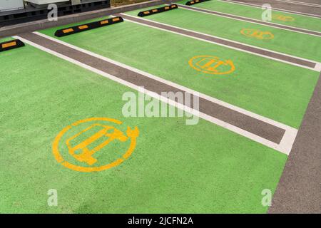 Yellow electric car symbol on green asphalt. Electric vehicle charging parking Stock Photo