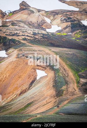 Laugavegur hiking trail is the most famous multi-day trekking tour in Iceland. Landscape shot from the area around Landmannalaugar, starting point of the long-distance hiking trail in the highlands of Iceland. Two hikers in front of a dream scenery. Stock Photo