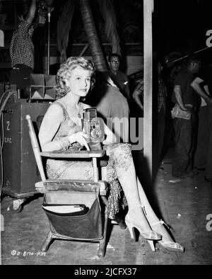 RITA HAYWORTH on set candid with Still Camera during filming of MISS SADIE THOMPSON 1953 director CURTIS BERNHARDT from story by W. Somerset Maugham screenplay Harry Kleiner gowns Jean Louis producer Jerry Wald The Beckworth Corporation / Columbia Pictures Stock Photo
