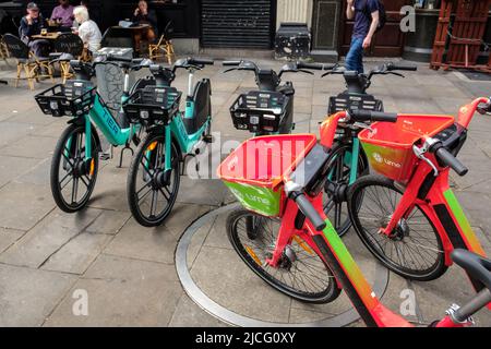 Lime and Tier  electric city bikes for hire parked on Cowcross Street pavement in the City of London Stock Photo