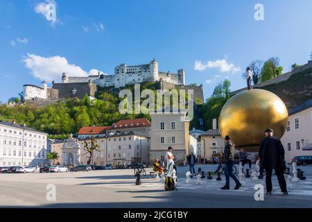 Salzburg, Hohensalzburg Fortress, square Kapitelplatz, Sphaera, a male figure standing on a huge golden sphere by Stephan Balkenhol, chess people in Flachgau, Salzburg, Austria Stock Photo