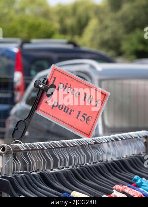 red price tag on a clothes rack at a market showing the price per piece, 1 piece 10 euros and in French it says 2 for 15 euros Stock Photo