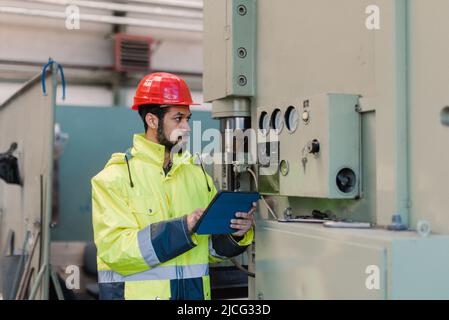 Portrait of engineer male using tablet while checking machines in industrial factory. Stock Photo