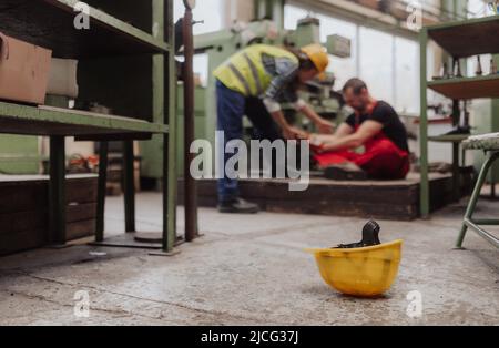 Woman is helping her colleague after accident in factory. First aid support on workplace concept. Stock Photo