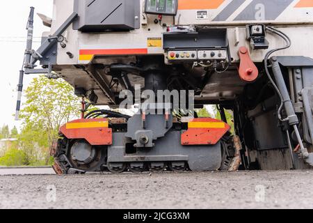 Large Road cold milling machine removes the old asphalt and loading  Stock Photo