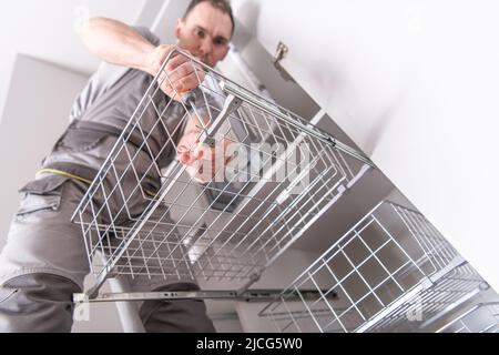 Caucasian Handyman in His 40s Screwing a Movable Shelf with His Screwdriver During the Process of Assembling a Large Closet in an Apartment. Stock Photo