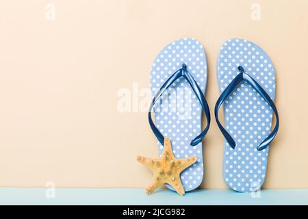 Beach accessories. Flip flops and starfish on colored background. Mock up with copy space. Stock Photo
