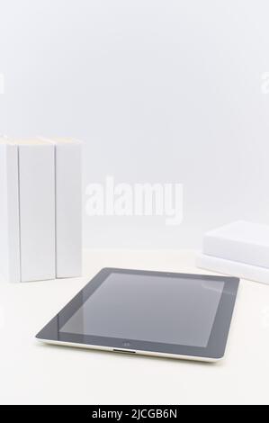 Apple ipad first generation on a bright desk with books against a white wall Stock Photo