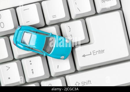 Small blue car on the computer keyboard. Car business concept such as transportation, rental, sell and buy. Stock Photo