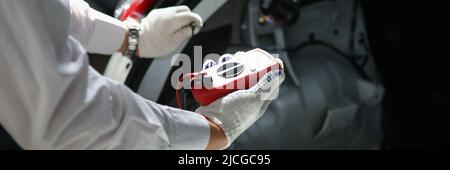 Mechanics hand using multimeter to measure voltage of car battery Stock Photo