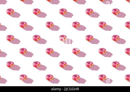 pattern made of Freshly baked donuts  with icing and sprinkles for breakfast on white background . Sweet background. Bakery, baking concept. Stock Photo
