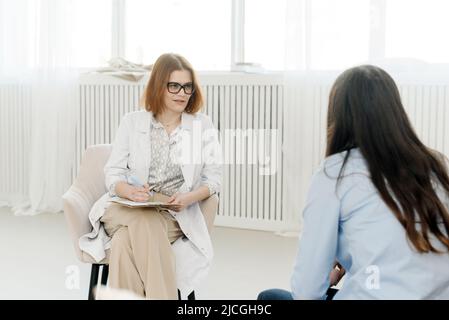 Psychotherapist's consultation. The counselor is talking to a young woman at a psychological session in the office, giving advice to a young client Stock Photo