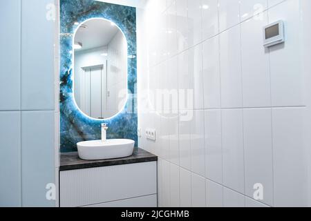 Contemprary bathroom interior with light mirror and sink table Stock Photo