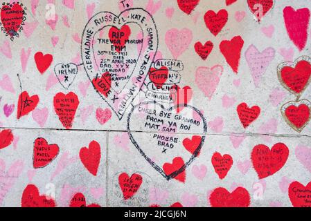 National Covid Memorial Wall in Lambeth, London, UK. Red hearts drawn onto a wall representing each death from COVID 19, with added names.